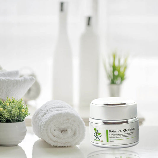 Botanical Clay Mask jar on a white surface with towels and plants in the background