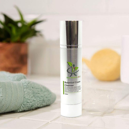 Skincare bottle labeled 'Botanical Cream Cleanser' on a bathroom counter with a towel and lemon in the background.